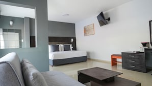 A modern hotel room with a bed, a sofa, a coffee table, a dresser, and a TV mounted on the wall. - Days Inn by Wyndham Minatitlan (Minatitlán)