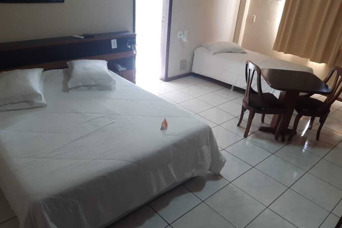 A hotel room with a large bed, a small table, and two chairs.