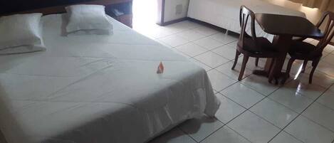Una habitación de hotel con una cama grande, una mesita pequeña y dos sillas.