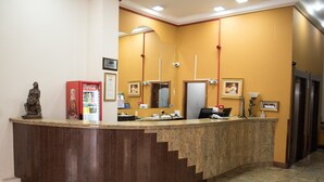 A reception area with a counter, a Coca-Cola refrigerator, and a statue.