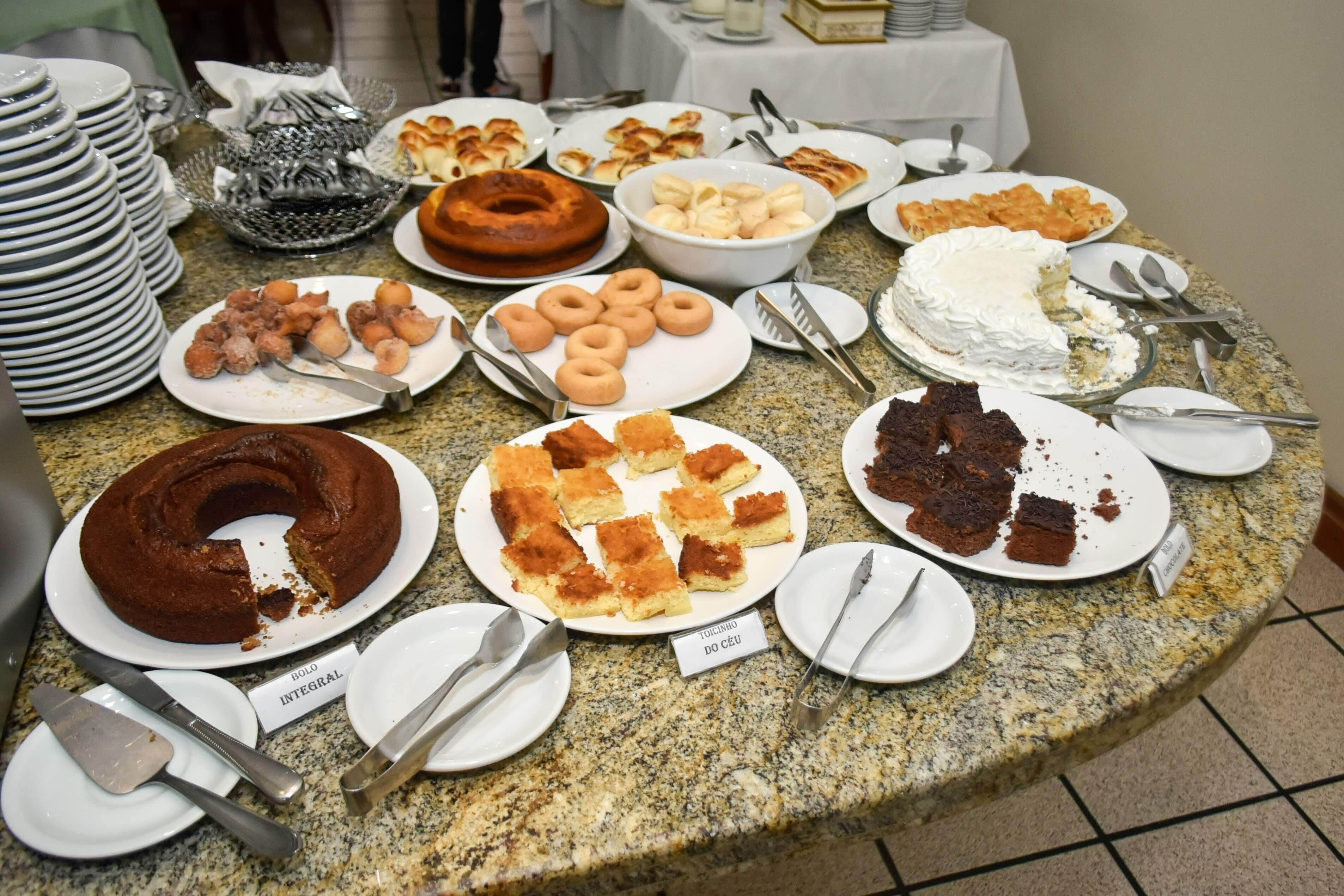A buffet table with various food items including cakes, pastries, and donuts.