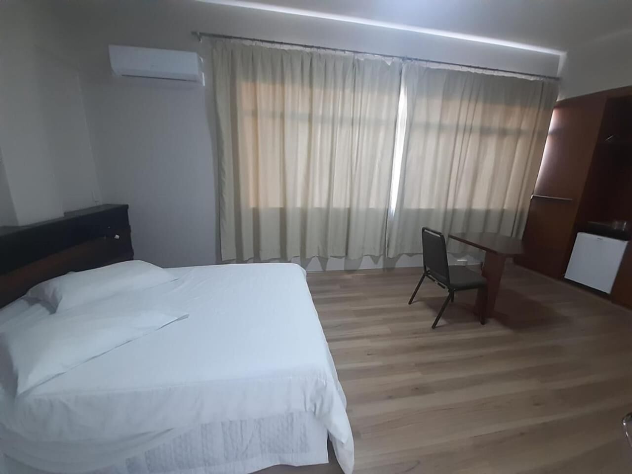 Une chambre d’hôtel avec un lit, un bureau et une chaise.