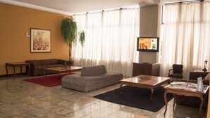 A living room with a sectional sofa, a coffee table, a TV, and a plant.