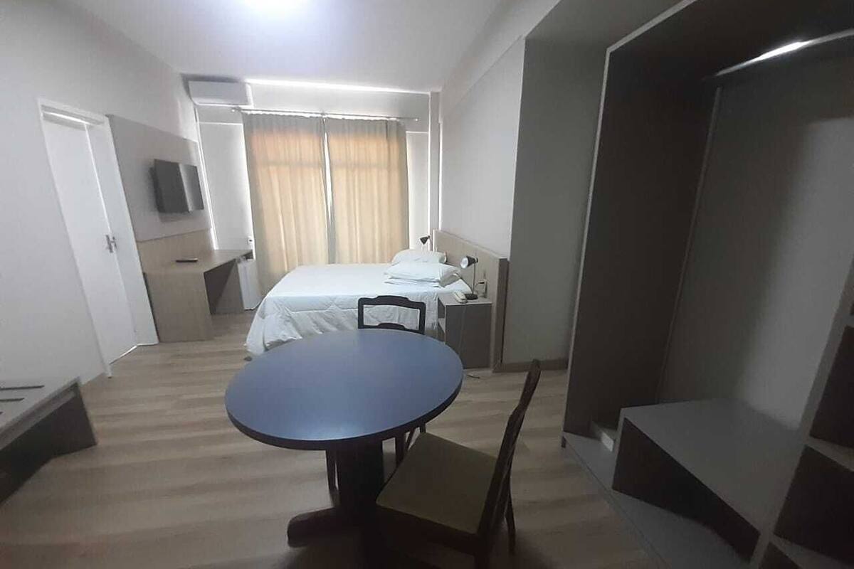 A hotel room with a bed, a small table, a chair, a wardrobe, and a television.