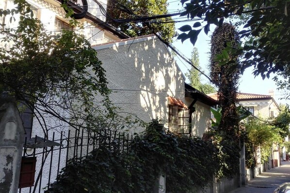 A narrow street with buildings on either side, covered in ivy, and a metal fence in the foreground. - JY Distributed Theme Hotel Apartment (Shanghai)