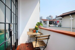 A balcony with a wooden table and chairs, a potted plant, and a view of buildings in the background. - JY Distributed Theme Hotel Apartment (Shanghai)
