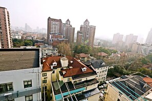 A high-rise building with multiple balconies and a rooftop terrace. - JY Distributed Theme Hotel Apartment (Shanghai)