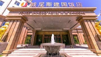 The entrance of Venice Jinguo Hotel in Dandong, featuring a prominent fountain and a large archway.