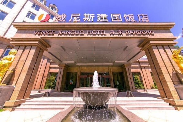 The entrance of Venice Jinguo Hotel in Dandong, featuring a prominent fountain and a large archway.