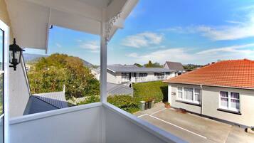 A balcony with a view of a residential area, including houses and greenery.