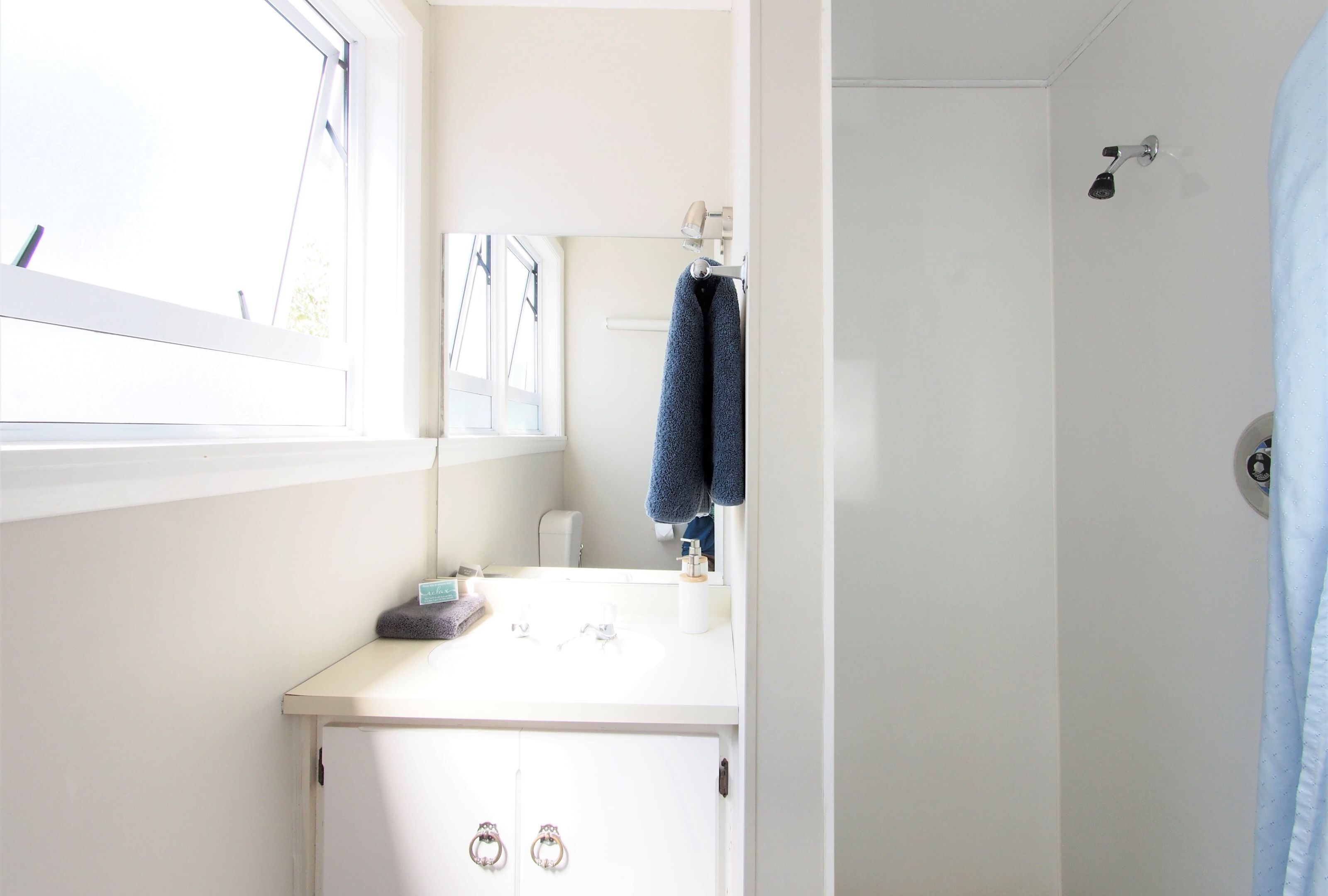 A bathroom with a white sink, a mirror, and a towel hanging on the wall.