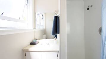 A bathroom with a white sink, a mirror, and a towel hanging on the wall.