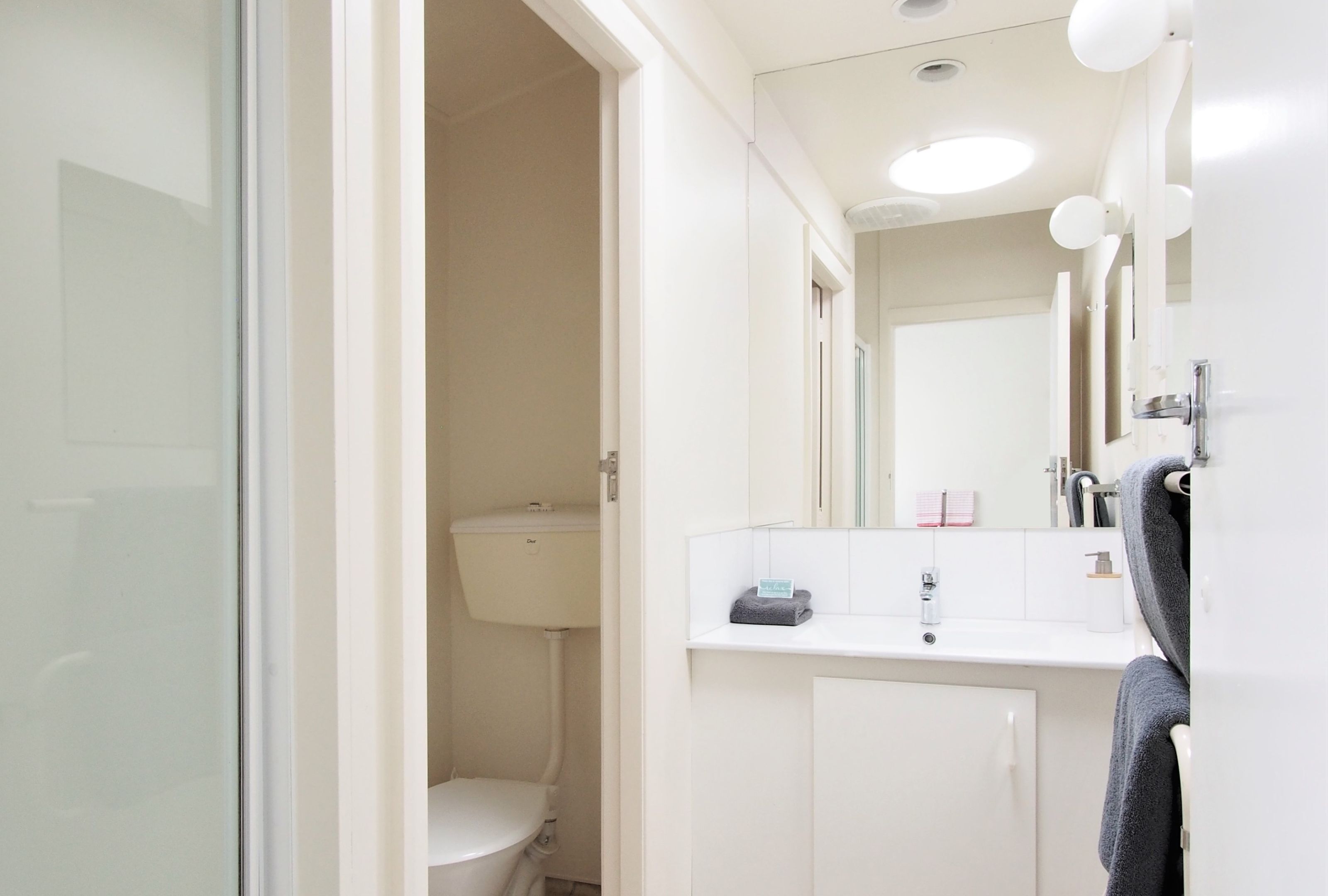 A bathroom with a toilet, sink, and mirror.