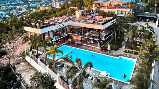 Un hôtel moderne doté d’une piscine sur le toit, d’un espace extérieur aménagé et offrant une vue sur la ville.