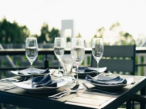A table set for dining with clear glassware and plates, outdoors with a view of greenery. - Son Tra Hill Phu Quoc (Phu Quoc)