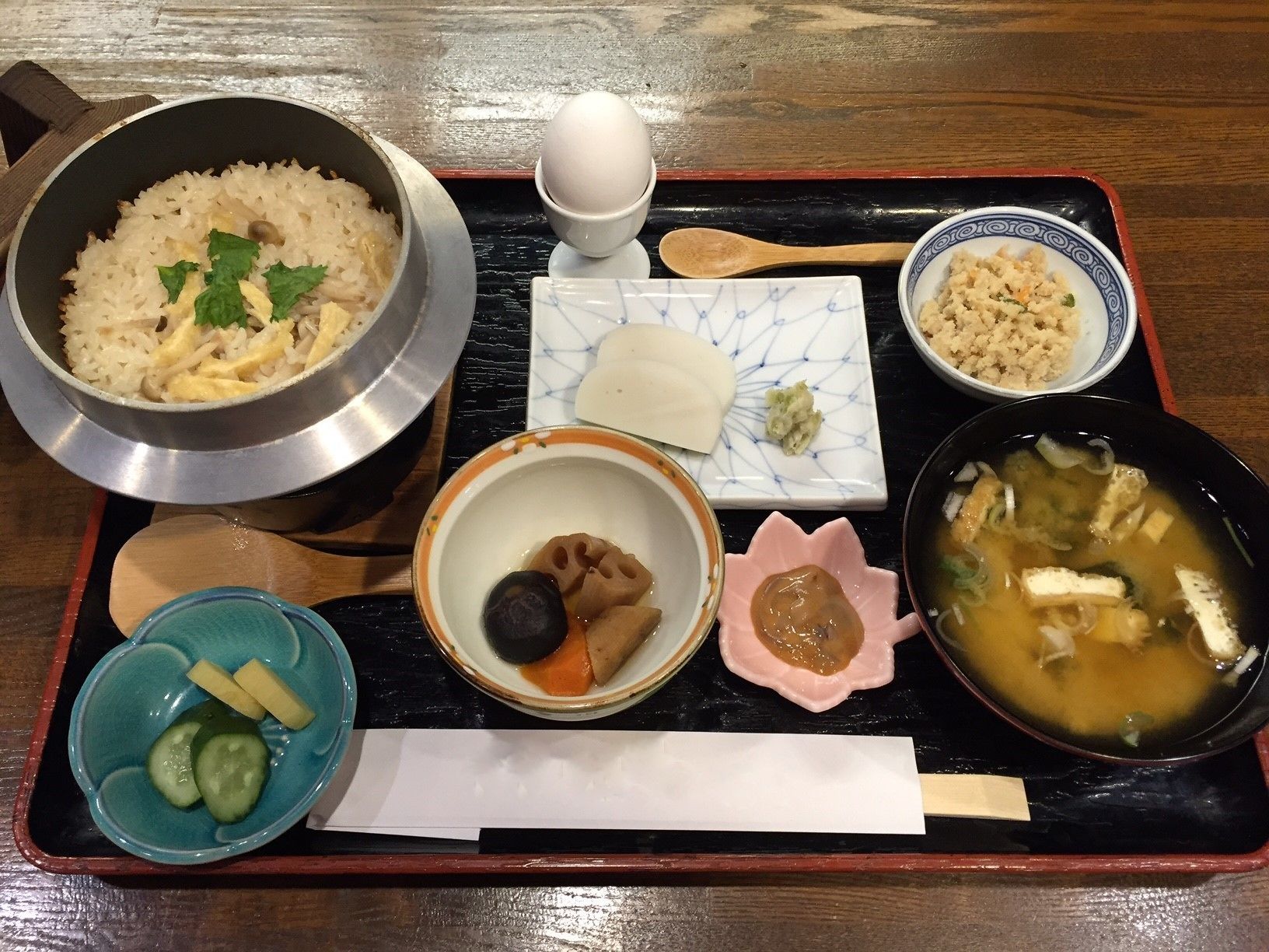A traditional Japanese meal on a tray, including rice, soup, pickles, and a small dish of tofu.