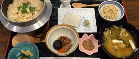 A traditional Japanese meal on a tray, including rice, soup, pickles, and a small dish of tofu.