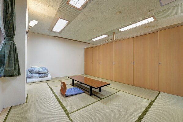 Una habitación con tatami, una mesa baja, cojines y puertas correderas.