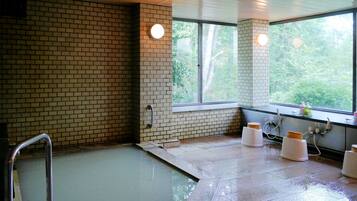 A bathroom with a bathtub, a window, and a sink area.