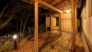 A wooden structure with a covered entrance, a stone pathway, and a lit signboard. - Hakone Gora Onsen Mizu no Kaori - Hostel (Hakone)