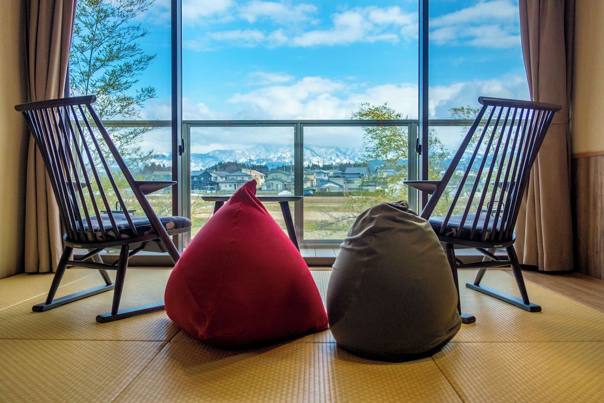 Two rocking chairs facing a large window with a view of a mountain and houses.