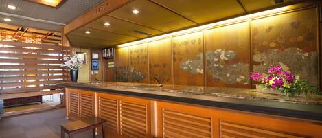 A reception area with a wooden counter, two wooden benches, and a decorative wall with floral patterns.