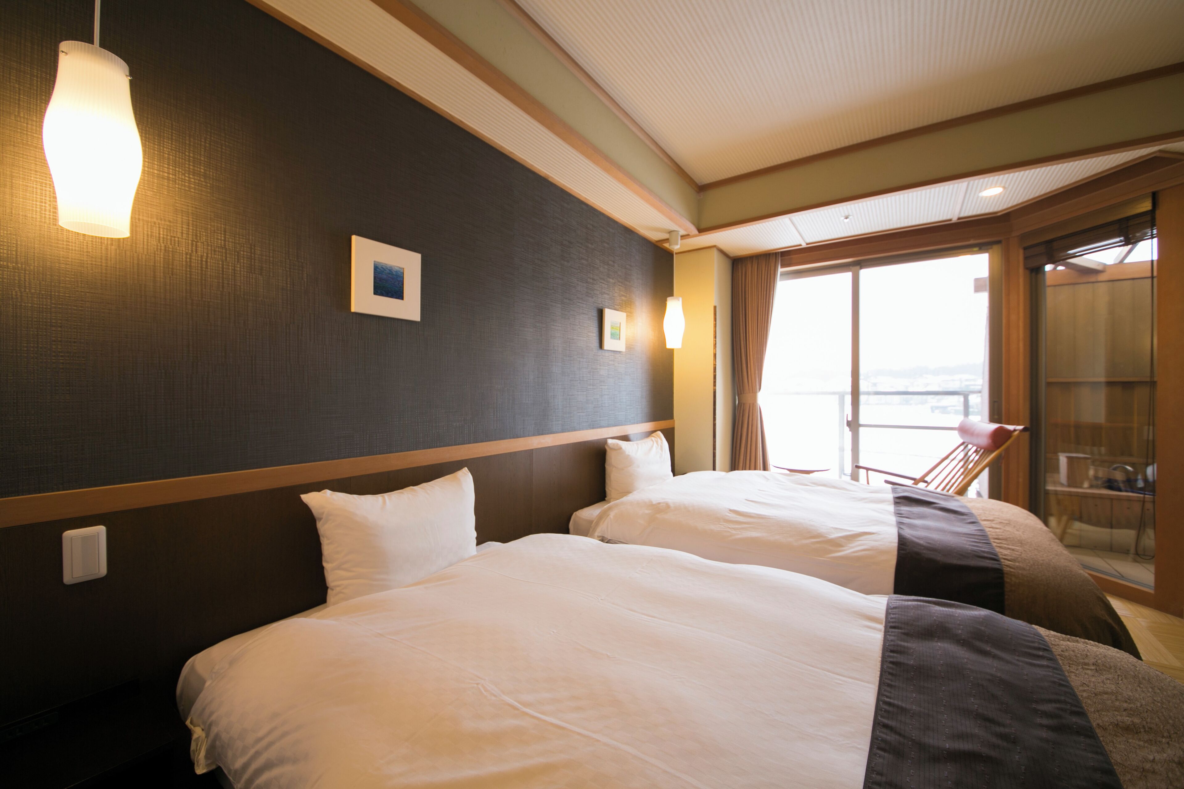 A hotel room with two beds, a large window, and a balcony.