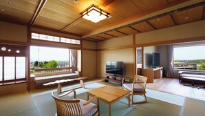 A traditional Japanese room with tatami flooring, a television, and a view of the city. - Kintarouonsen (Uozu)