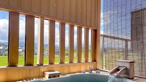 A hot tub with a view of a green landscape through wooden slats. - Kintarouonsen (Uozu)