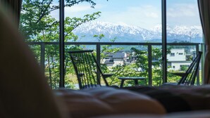 A room with a view of snow-capped mountains and a balcony with chairs. - Kintarouonsen (Uozu)