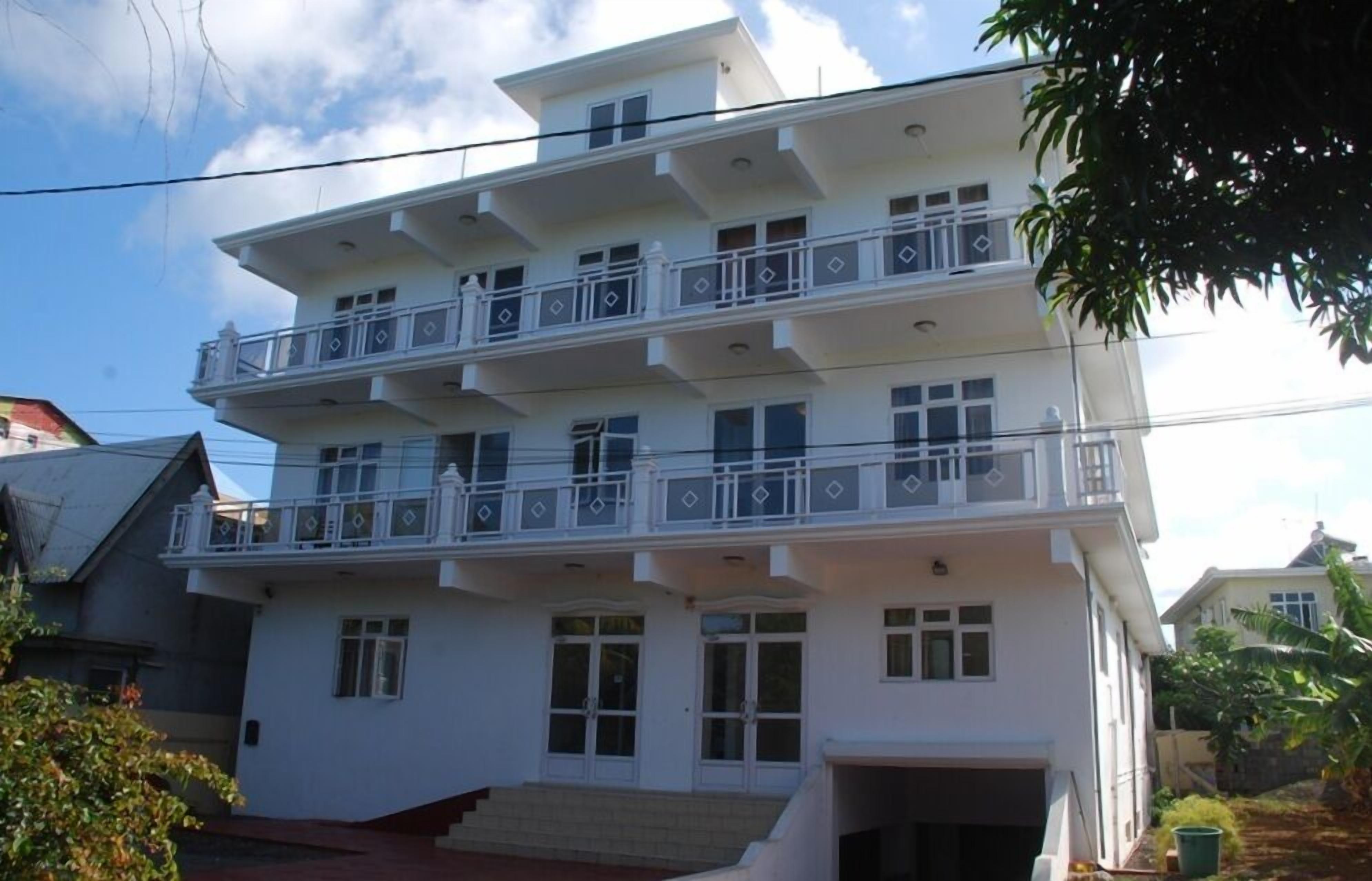A multi-story residential building with balconies, a garage, and a staircase leading to the entrance.