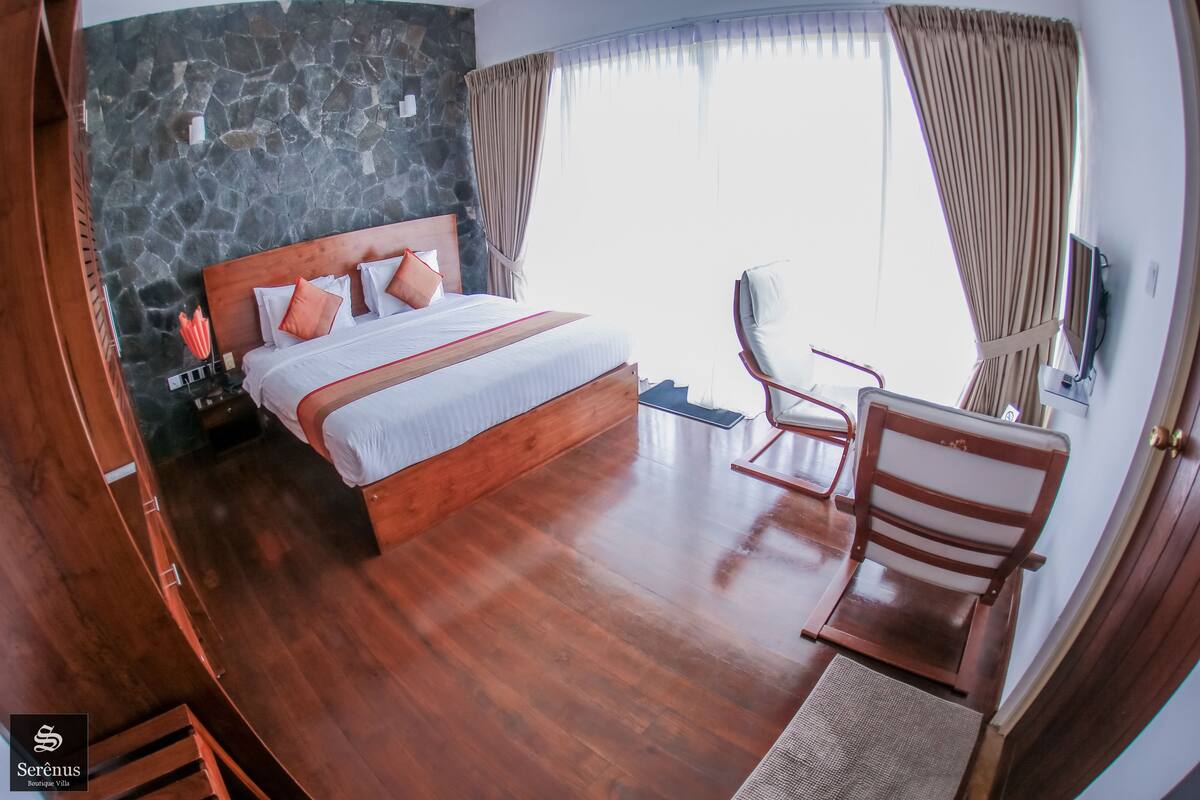 A bedroom with a wooden bed, stone wall, and a view of the outdoors.
