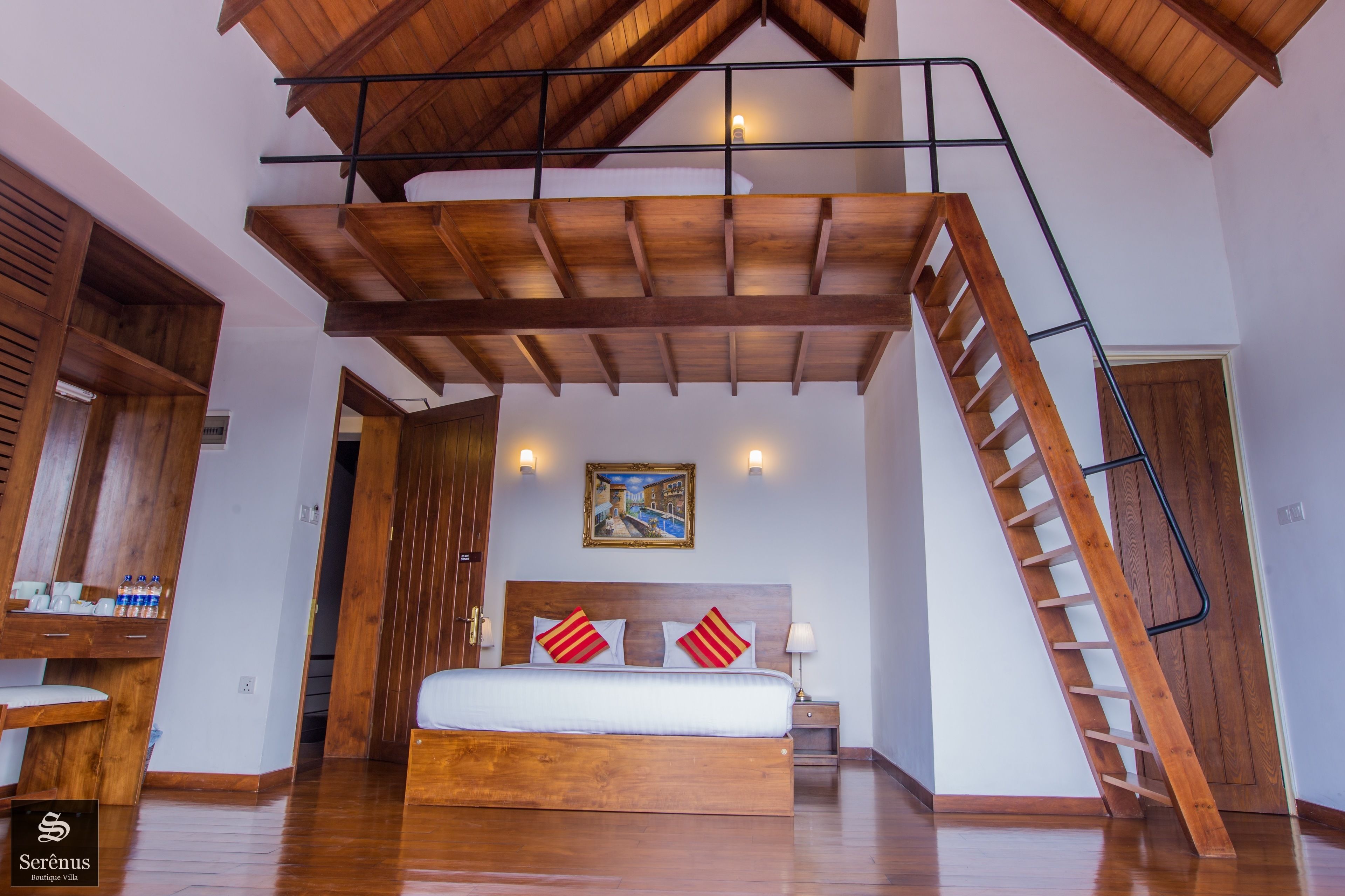 A bedroom with a wooden bed, a sloped ceiling, a staircase, and a painting on the wall.