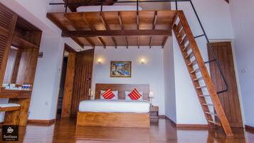 A bedroom with a wooden bed, a sloped ceiling, a staircase, and a painting on the wall.