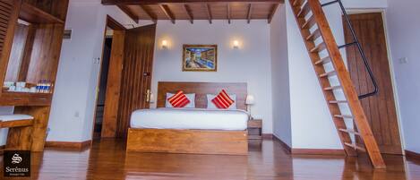 A bedroom with a wooden bed, a sloped ceiling, a staircase, and a painting on the wall.