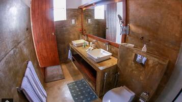 A bathroom with a wooden vanity, two sinks, a large mirror, a toilet, and a towel rack.
