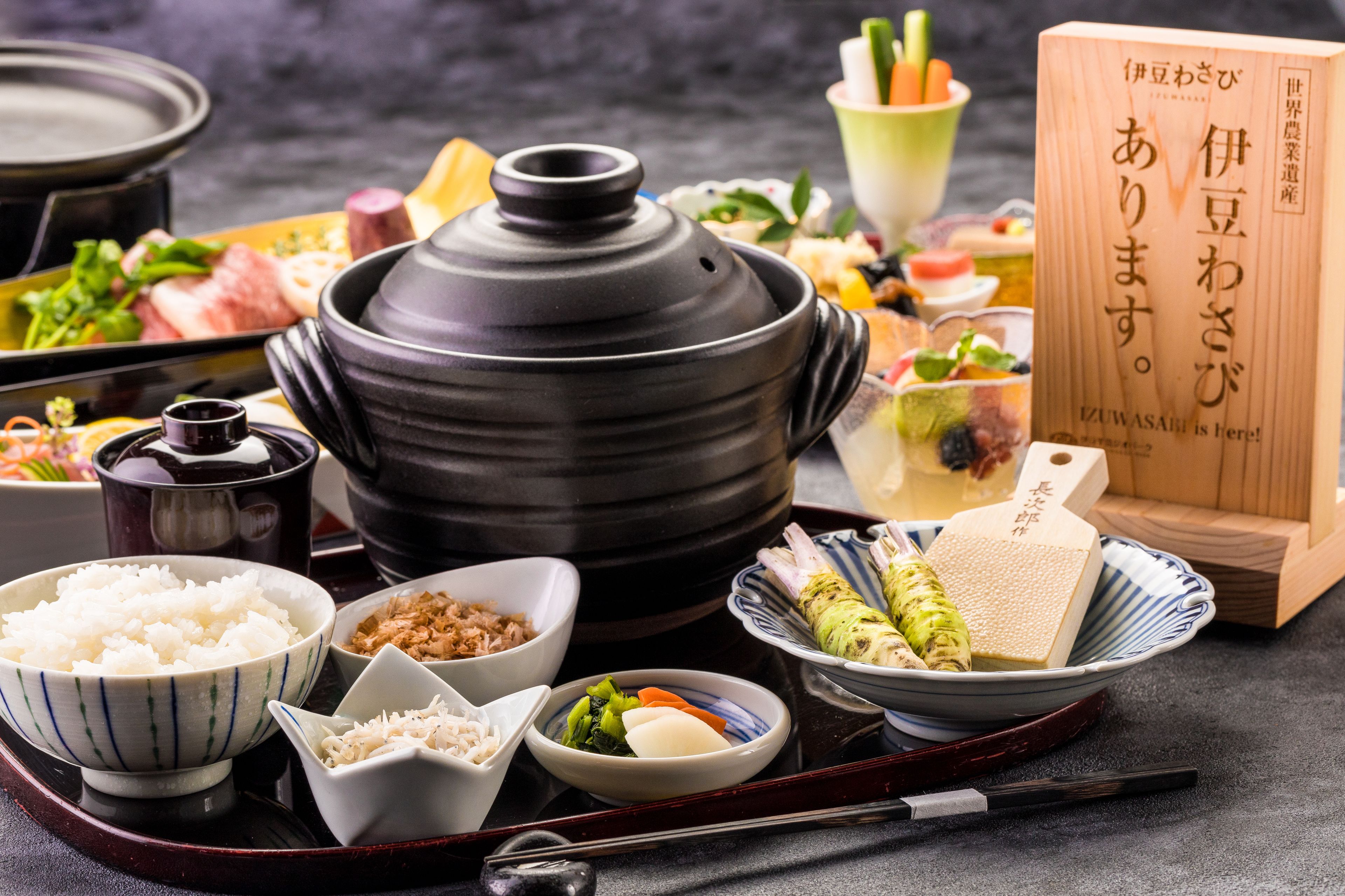 A traditional Japanese meal setup with a black pot, bowls of rice, and various side dishes.