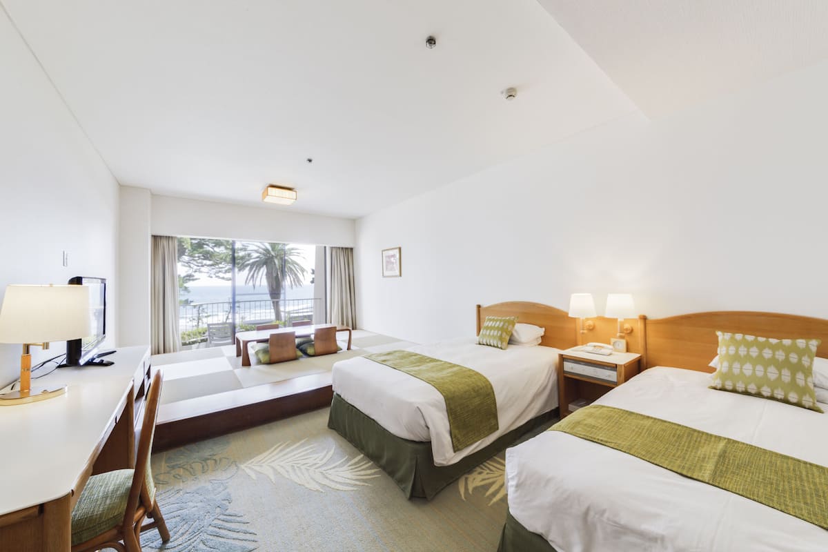 Een hotelkamer met twee bedden, een bureau, een stoel en een raam met uitzicht.