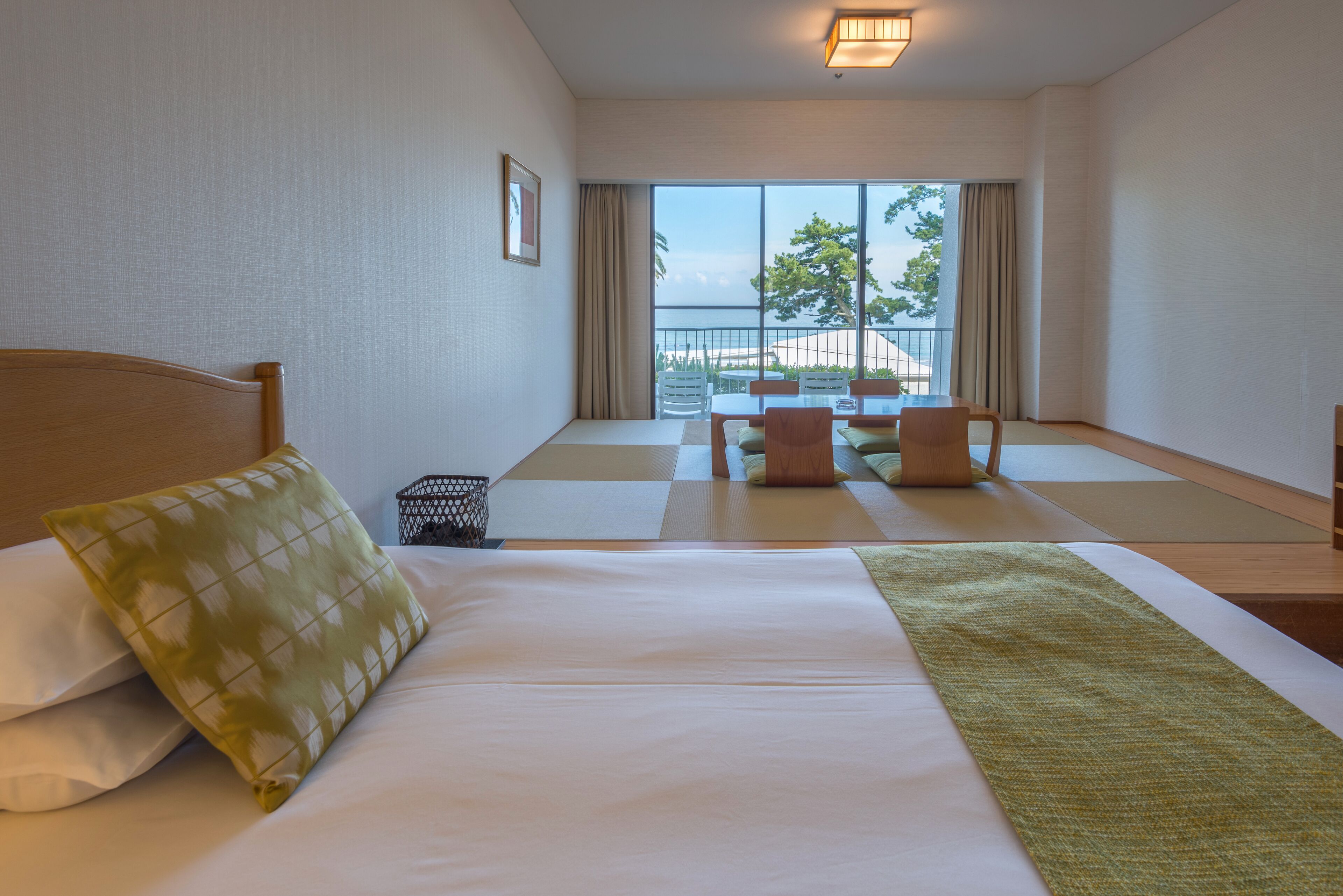 Habitación de hotel con una cama grande, vista al balcón y un área de descanso con sillas.