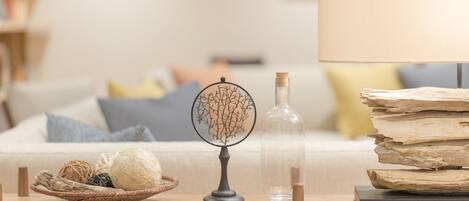 A wicker side table with a decorative tree, a clear bottle, and a stack of books.