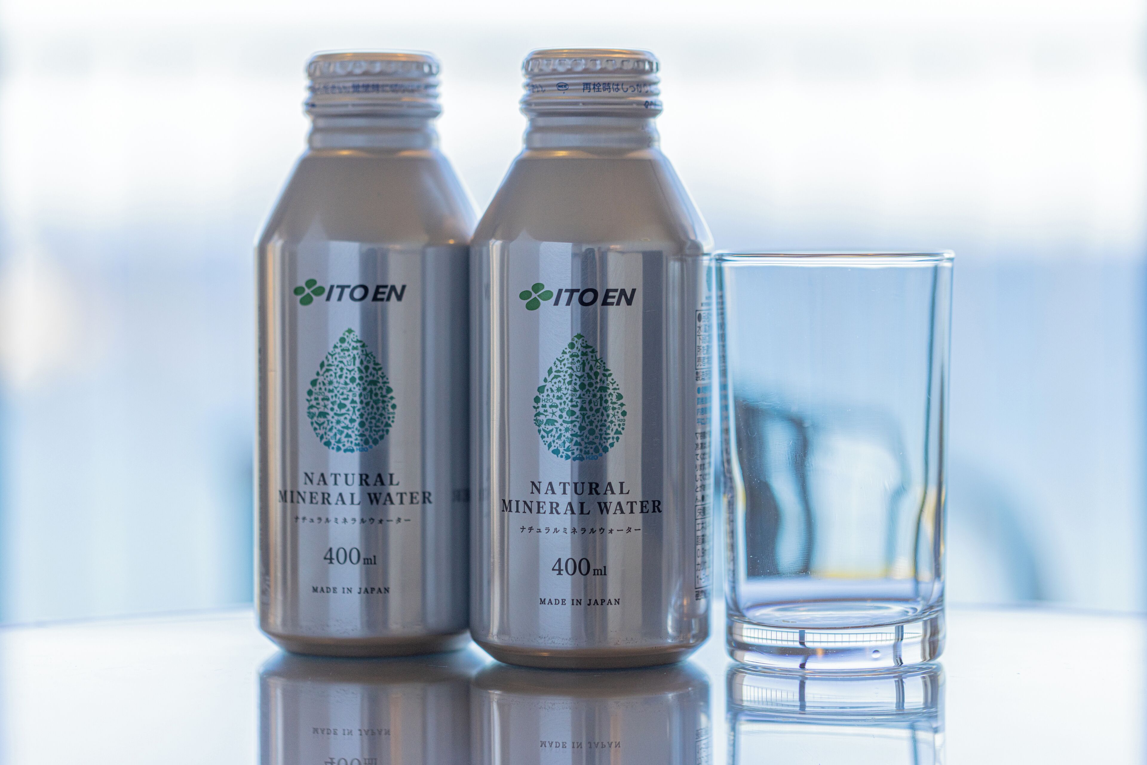 Two bottles of ITOEN natural mineral water and a clear glass.