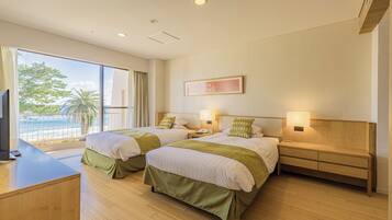 A hotel room with two beds, a desk, and a view of the beach.