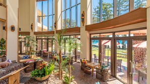 A spacious indoor area with large windows, outdoor seating, and a variety of plants.