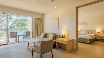 A hotel room with a balcony, a sofa, a desk, a bed, and a nightstand.