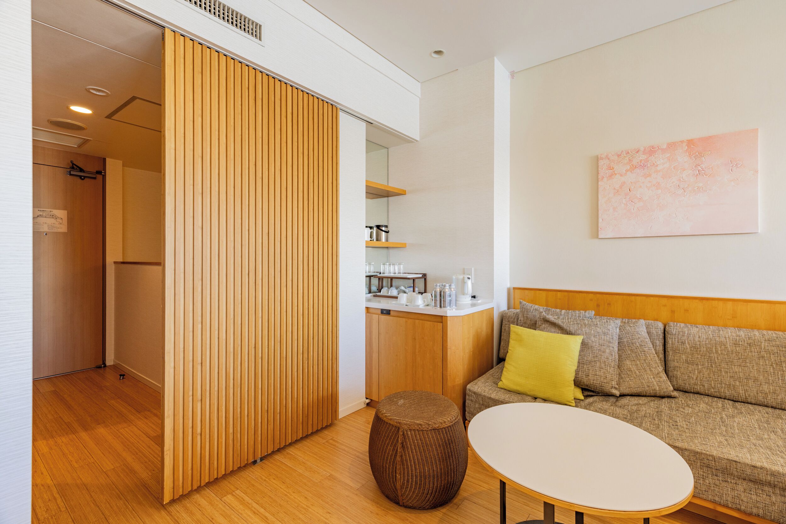 Un espacio moderno con un sofá, una mesa redonda y un separador de madera.