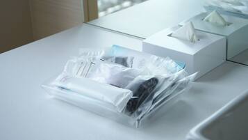 A hotel room with a neatly arranged bathroom counter, a tissue box, and a bag of toiletries.