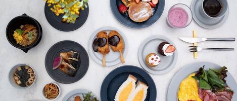 Variedad de platillos y bebidas sobre una mesa, entre ellos, waffles, panqueques y una ensalada.