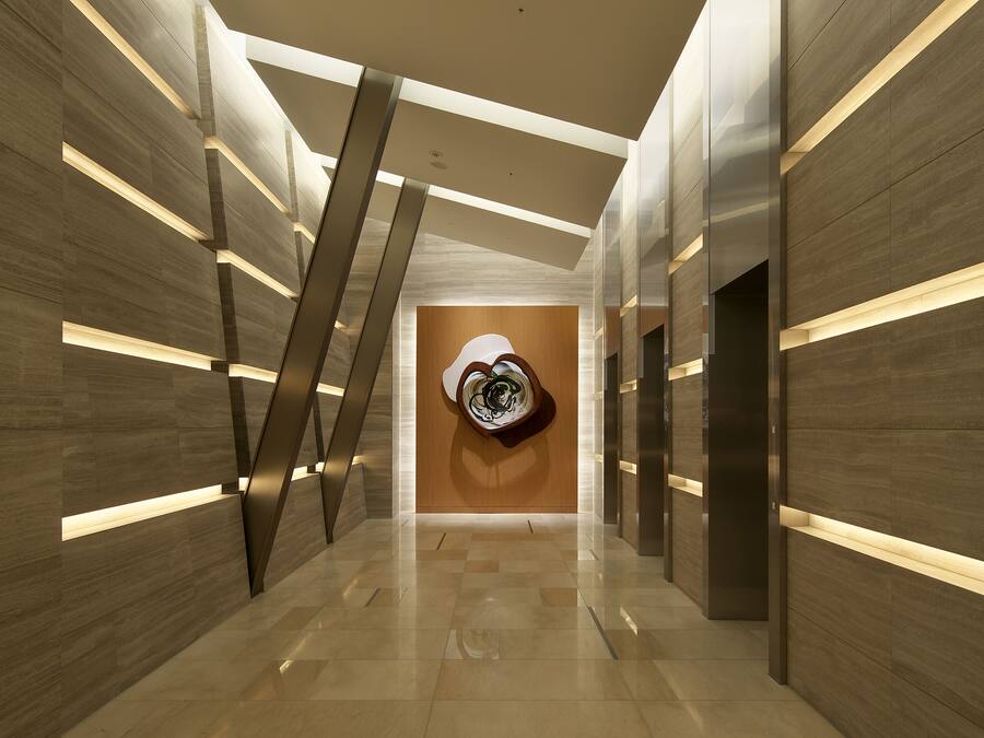 Un pasillo moderno con paneles de madera, una obra de arte central y una escalera.