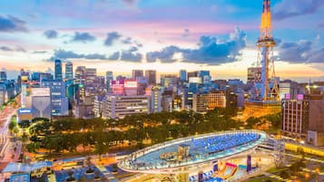 A cityscape with a prominent tower, a large circular plaza with seating, and surrounding buildings.