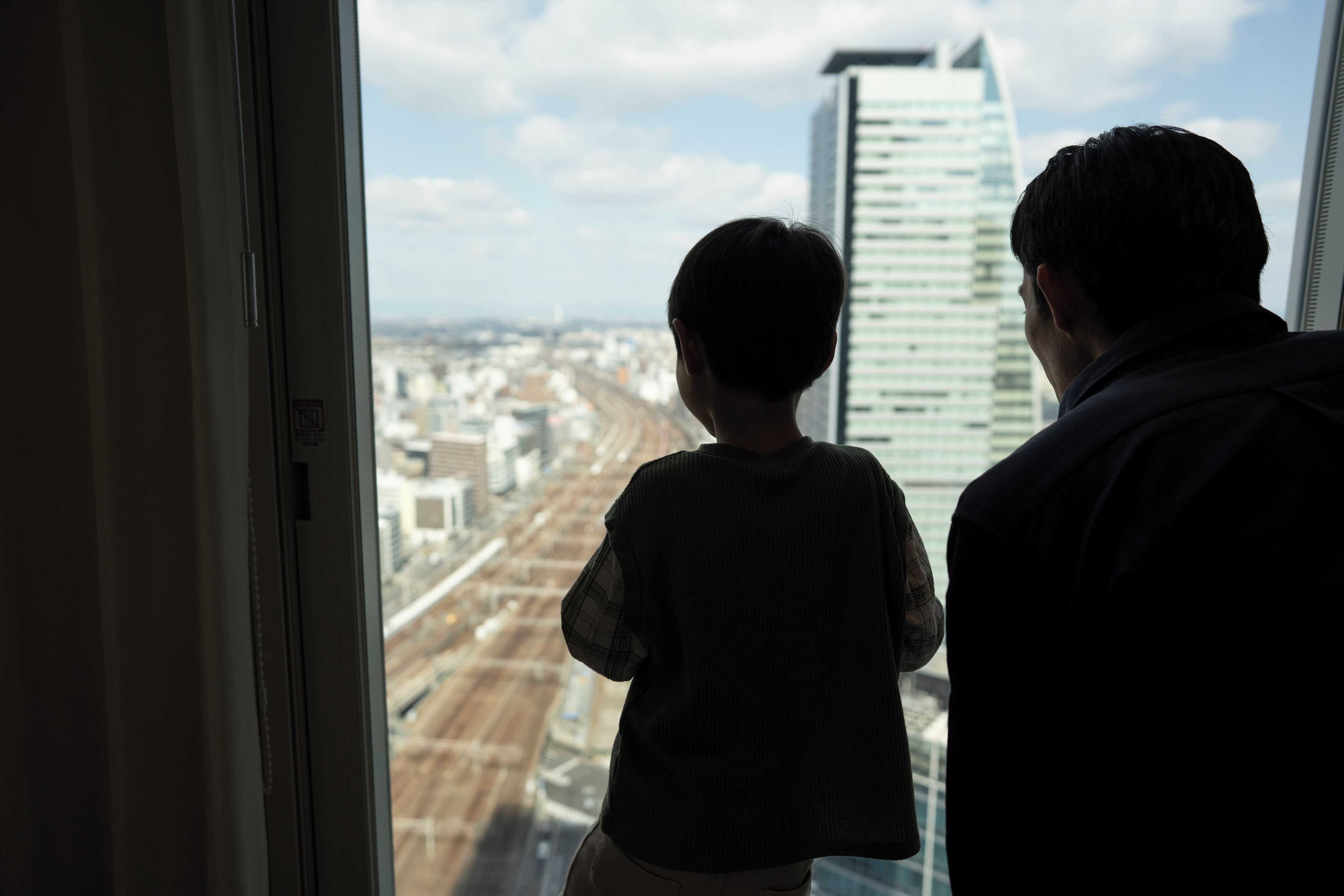 A view from a window overlooking a cityscape with tall buildings and a road.